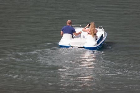 The guy with the girl in the boat on the surface of the lake water .