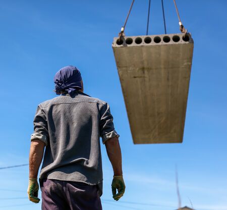 A crane raised a concrete slab at a construction site at home .