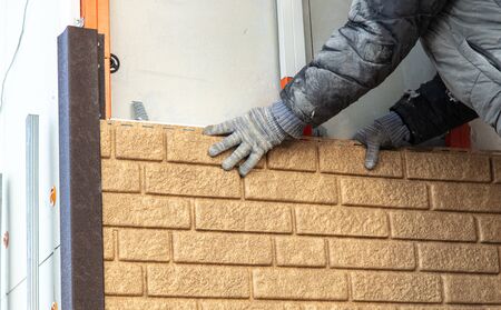 Worker installs plastic panels with bricks .