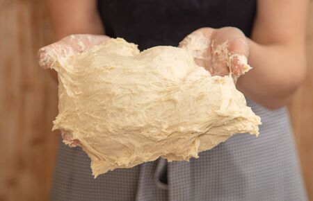 Mistress kneads the dough in the kitchen .