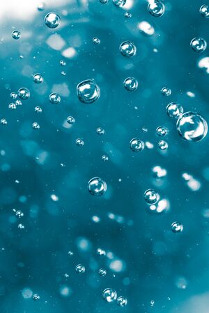 Bubbles of air on the smooth surface of blue water as an abstract background .
