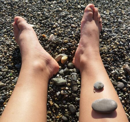 Men's feet on a pebble beach by the sea .の写真素材