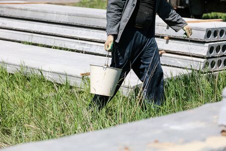 Worker with buckets of concrete at a house construction .