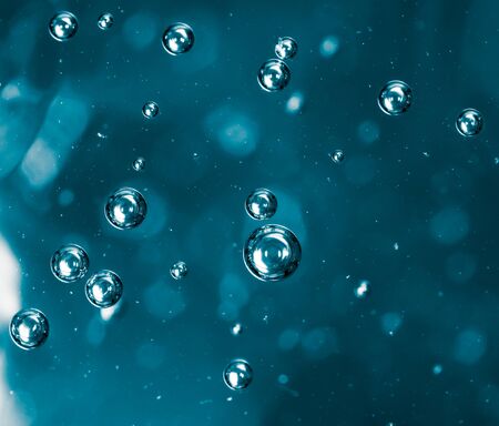 Bubbles of air on the smooth surface of blue water as an abstract background .