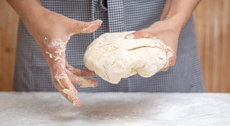 Mistress kneads the dough in the kitchen .