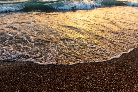 Waves on the seashore at sunset.の写真素材