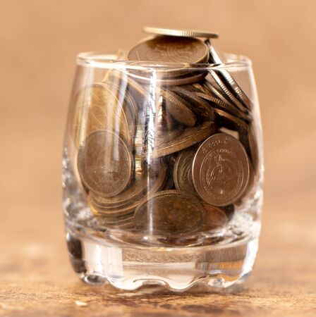 Coins in a glass cup on a marble table .の写真素材