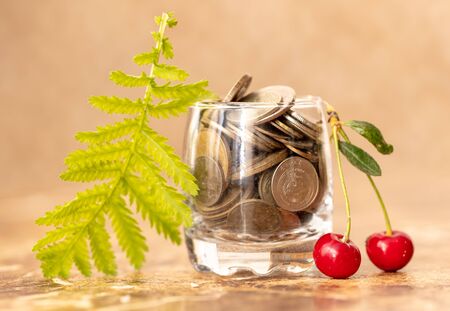 Red cherries in coins in a glass beaker .