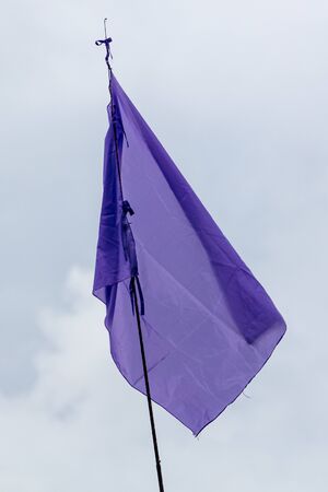 Purple flag on gray sky background .の写真素材