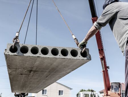 A crane raised a concrete slab at a construction site at home .
