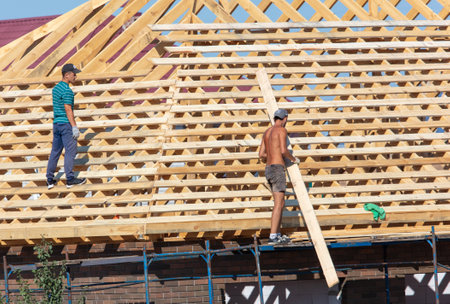 Lipetsk, Russia - August 30, 2019: Workers work with a tree on the roof of the house. Construction of the cottage.のeditorial素材