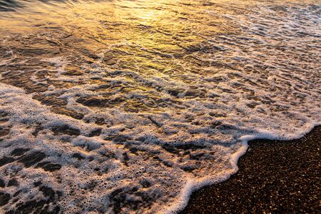 Waves on the seashore at sunset.の写真素材