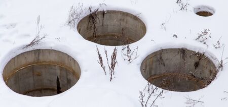Sewer manholes in the snow in winter.の写真素材