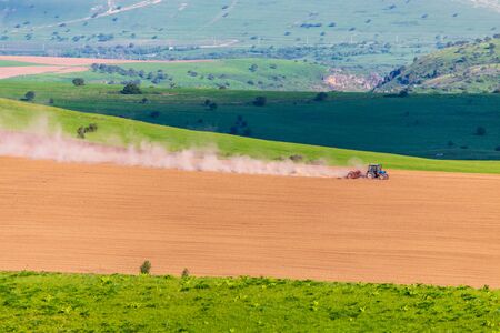 Dust from a tractor working in a field in spring .の写真素材