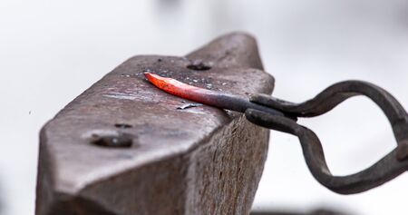 A blacksmith bends metal with a hammer.の写真素材