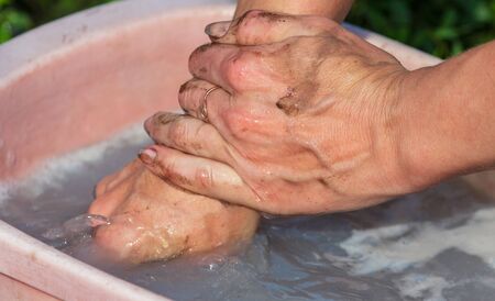 Washing dirty hands in a basin in nature.の写真素材