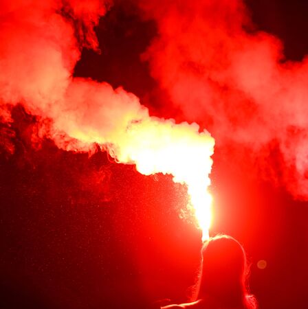 Red smoke bomb in a girlâs hand at night.の写真素材