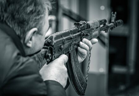 A man shoots with a gun. Black and white photo