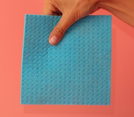 Blue rag in hand on a pink background.