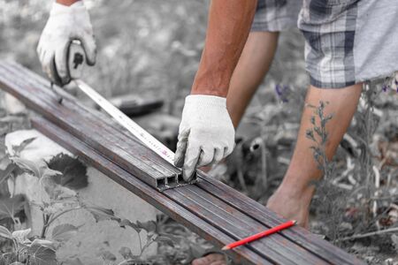 A worker measures metal at a construction site.の写真素材