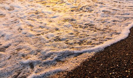 Waves on the seashore at sunset.の写真素材