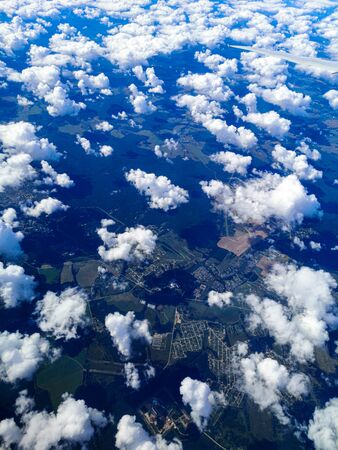 Clouds above the ground view from an airplane as a background.