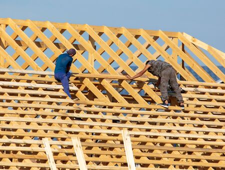 Workers are building the roof of the house from wood.
