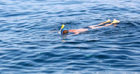 A man swims in the blue water of the sea.の写真素材