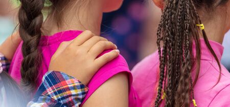 Hands on the shoulders of a girl with pigtails. Children play in the parkの写真素材