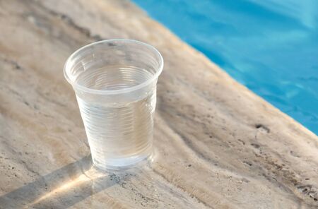 Plastic glass with water near the pool.の写真素材