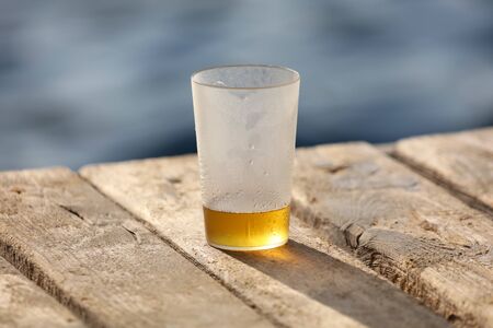 Glass with beer near the water on the beach.の写真素材