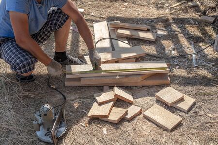 Worker measures a wooden board at a construction site.