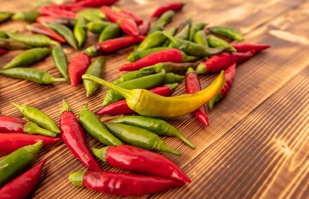 Green and red chili peppers on a wooden board.