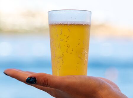 Glass with beer in the girlâs hand.の写真素材