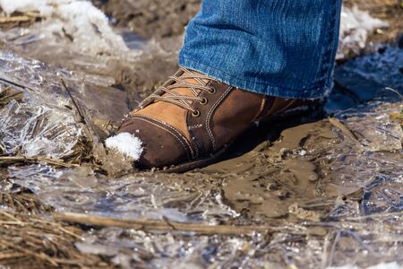 Legs of a man in shoes and jeans on the snow in winter.