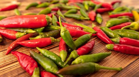 Green and red chili peppers on a wooden board.