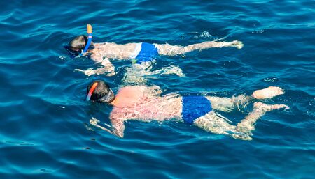 People swim in the blue water of the sea.の写真素材