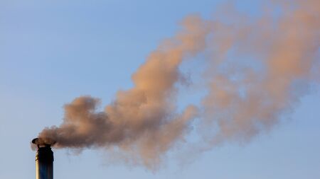 Smoke from the chimney of a house at dawn of the sun in winter.の写真素材