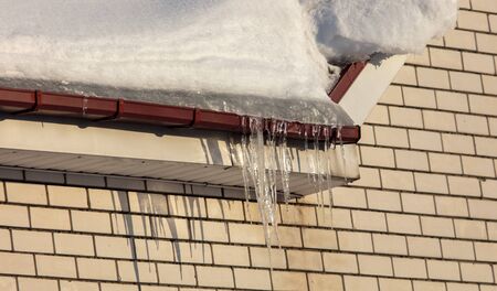 Brick house with snow on the roof in winter.