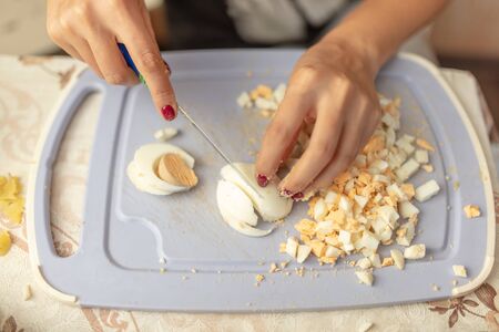 The girl cuts a boiled egg with a knife.