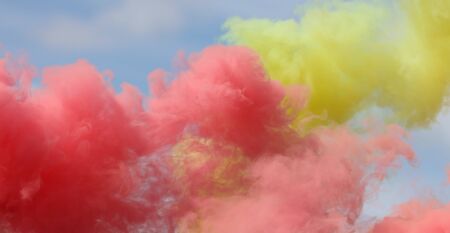 Red and yellow smoke on a blue sky.の写真素材
