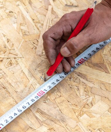 Worker measures the board at a construction site.の写真素材
