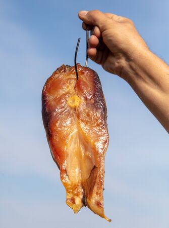 Smoked fish in a man's hand.の写真素材