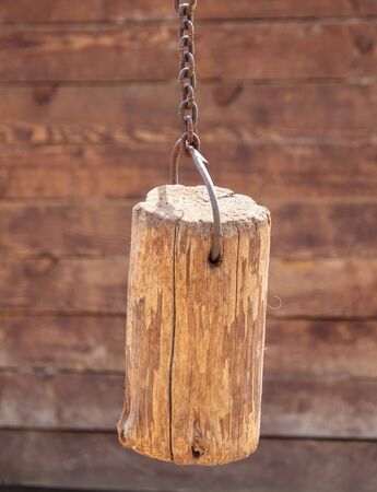A wooden beam hangs on a metal chain.の写真素材