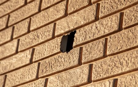 Wall of plastic yellow brick with a hole.の写真素材