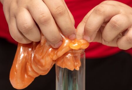 A boy plays with a slime in his hands.