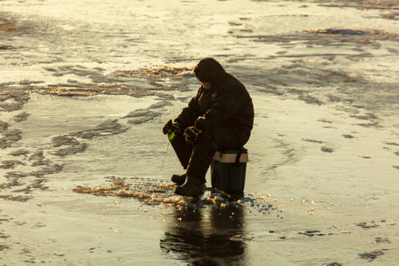 Lipetsk, Russia - December 6, 2019: A man catches fish on ice in the morning at the Matyr reservoir.のeditorial素材