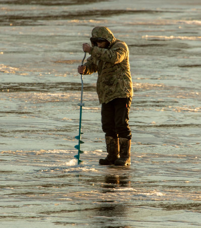 Lipetsk, Russia - December 6, 2019: A man catches fish on ice in the morning at the Matyr reservoir.のeditorial素材