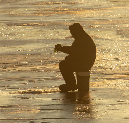 Lipetsk, Russia - December 6, 2019: A man catches fish on ice in the morning at the Matyr reservoir.のeditorial素材