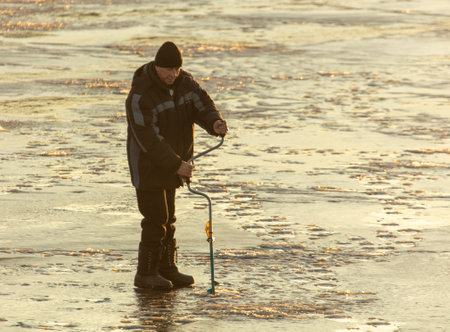 Lipetsk, Russia - December 6, 2019: A man catches fish on ice in the morning at the Matyr reservoir.のeditorial素材